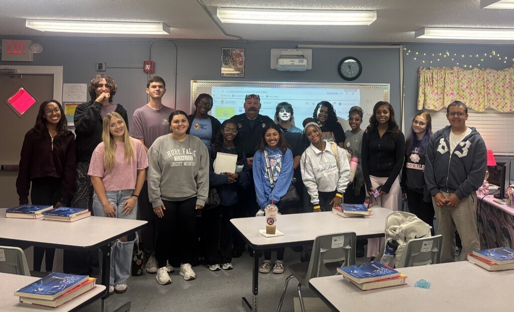 class of students posing for picture with firefighter