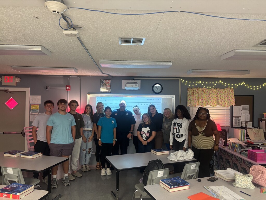 class of students posing for picture with firefighter