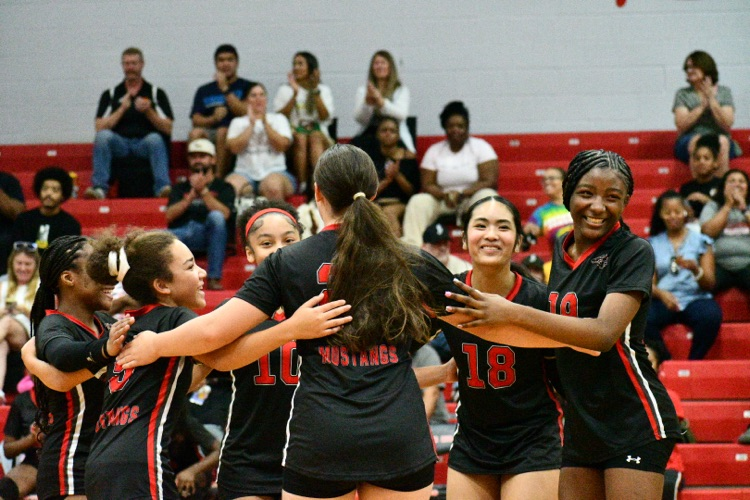 volleyball team in a circle celebrating.