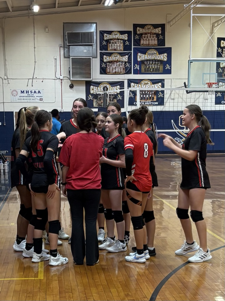image shows a group of volleyball players standing in a huddle.