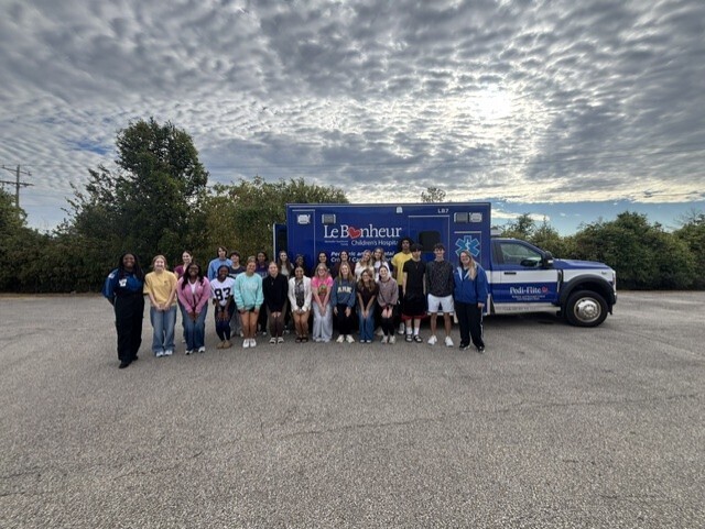 students posing in front of ambulance