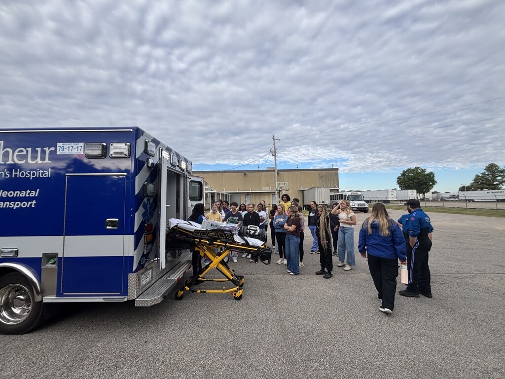 students posing in front of ambulance and gurney