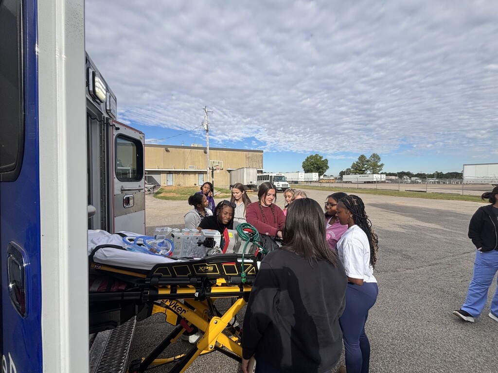 students posing in front of ambulance