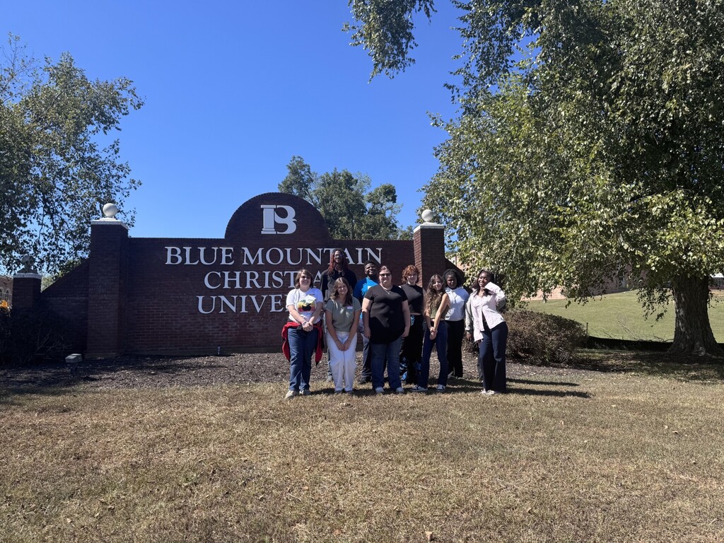 students posing in front of blue mountain university sign