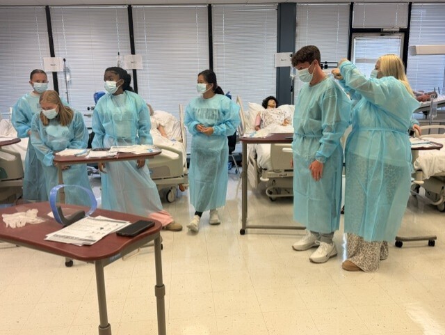 teacher and students in lab learning to put on protective 