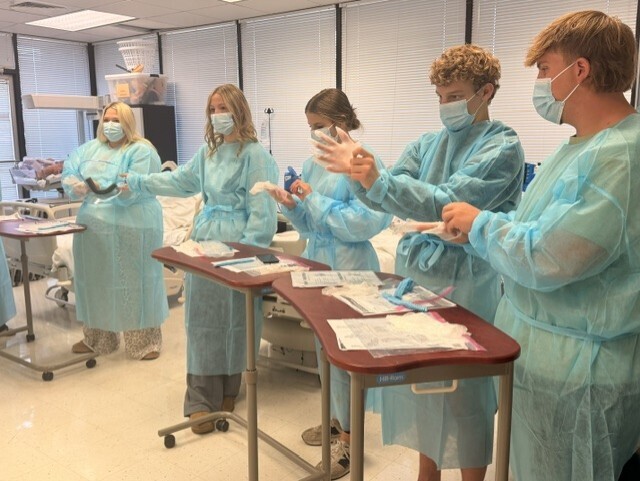 teacher and students in lab learning to put on protective 