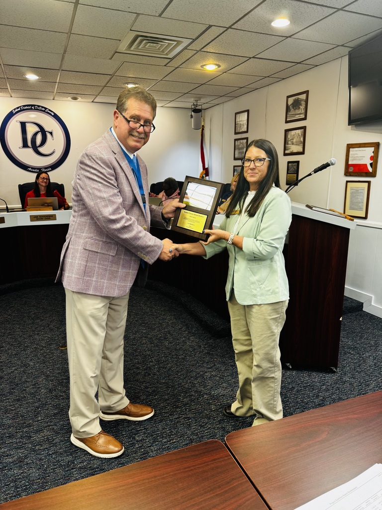 photo of Dr. Bennett, Superintendent presenting school board member with a plaque