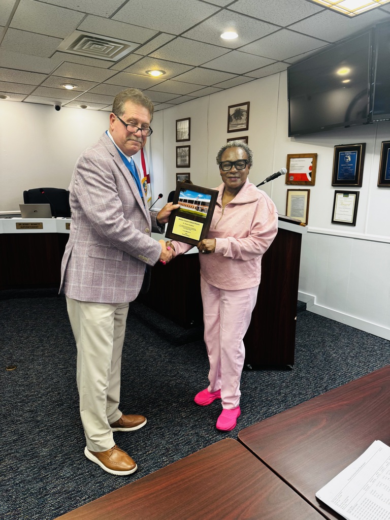 photo of Dr. Bennett, Superintendent presenting school board member with a plaque