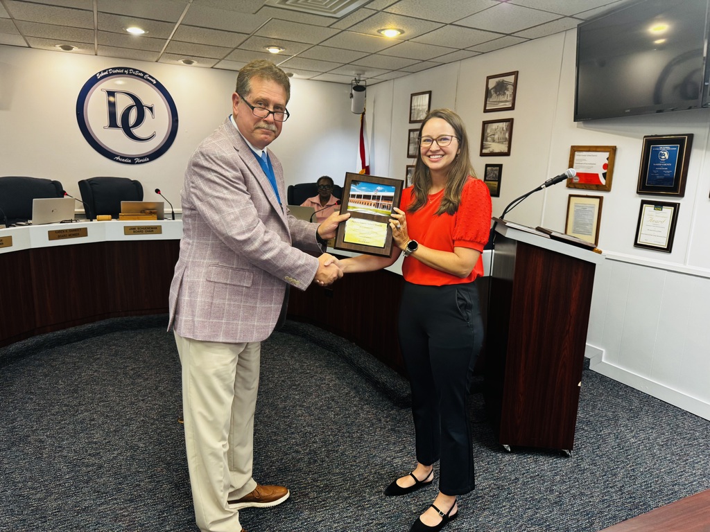 photo of Dr. Bennett, Superintendent presenting school board member with a plaque