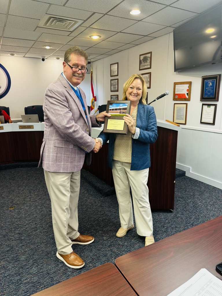 photo of Dr. Bennett, Superintendent presenting school board member with a plaque