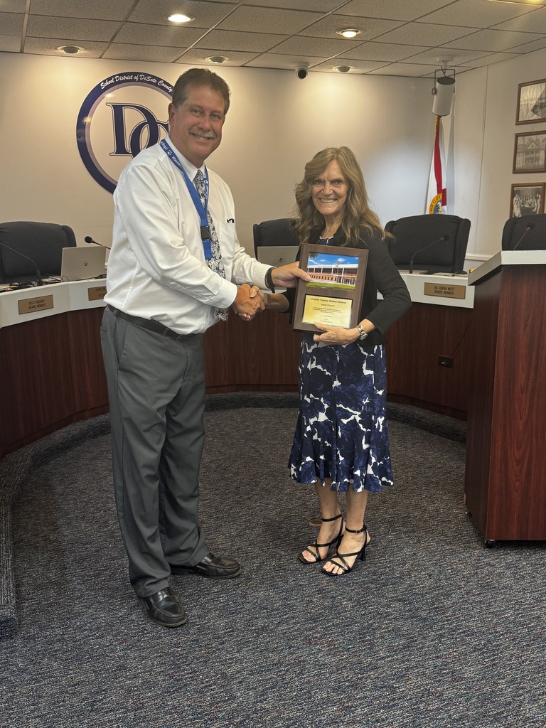 photo of Dr. Bennett, Superintendent presenting school board member with a plaque