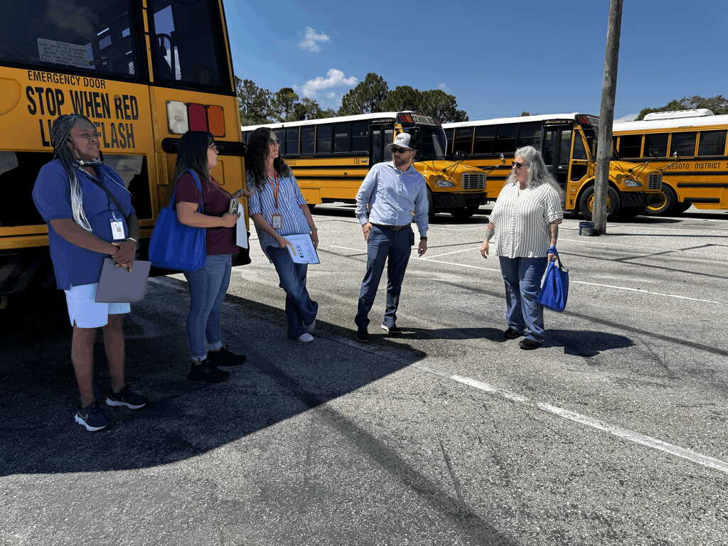 group of staff standing near a bus talking