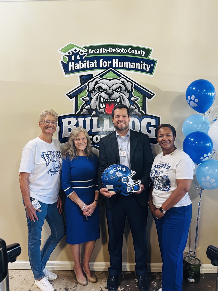 3 ladies and 1 man holding a football helment and posting for a picture standing in front of a bulldog sign with "Habitat for Humanity Bulldog Corner"