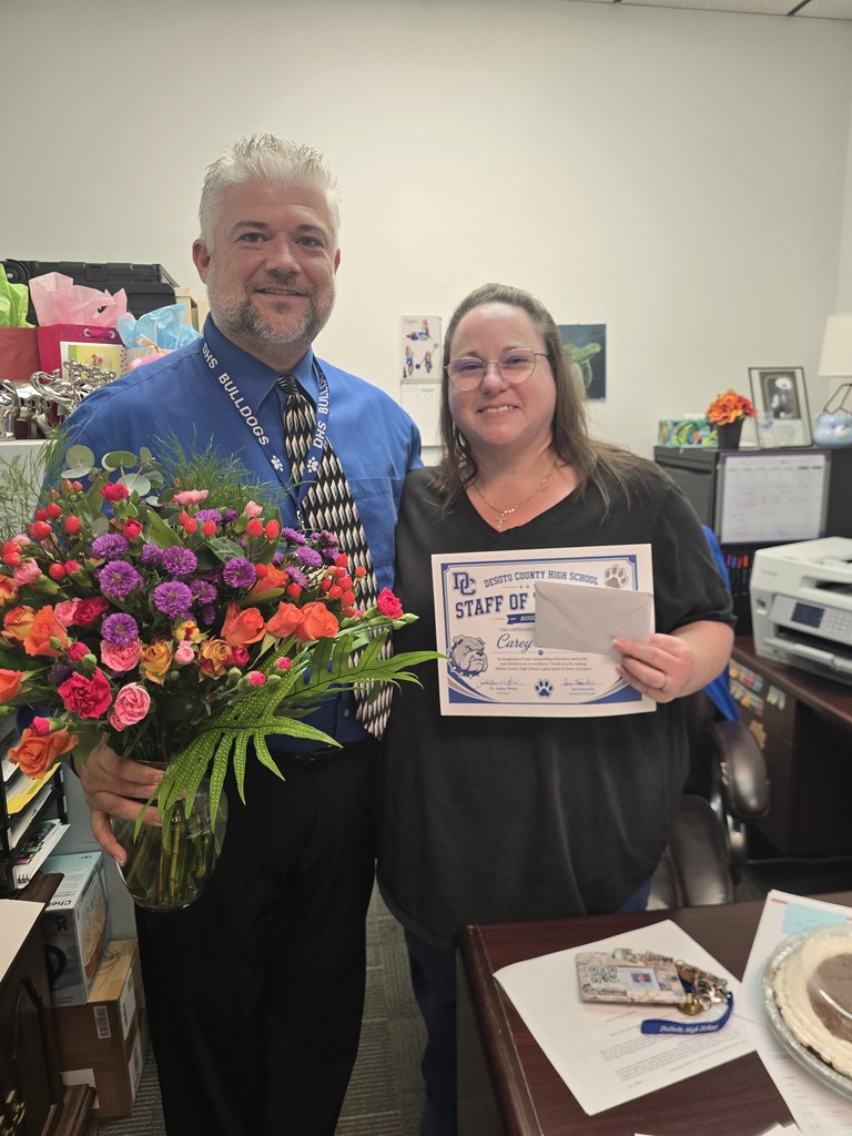 man in blue shirt holding flowers and woman in black shirt holding certificate