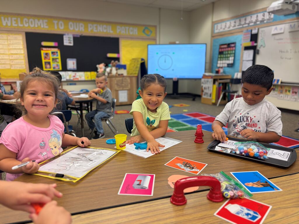three students sitting at table doing small group activity