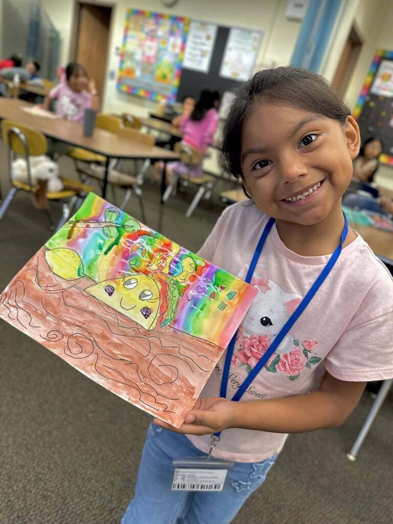 stuedent smiling holding artwork
