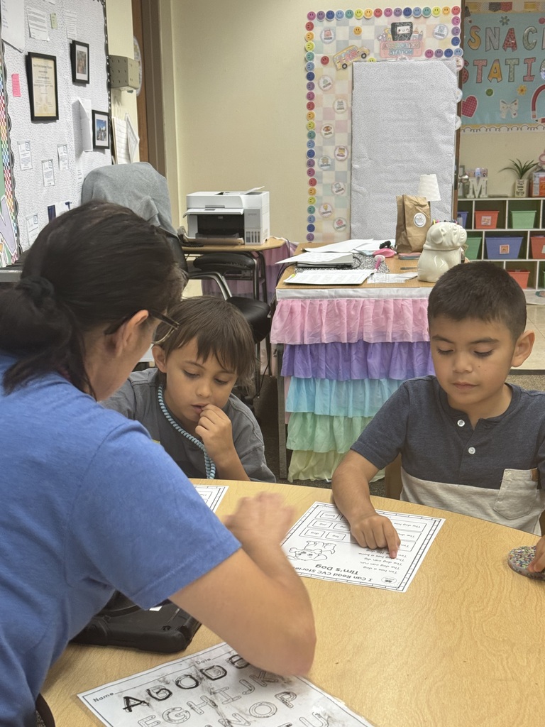 teache sitting at table with students review letters