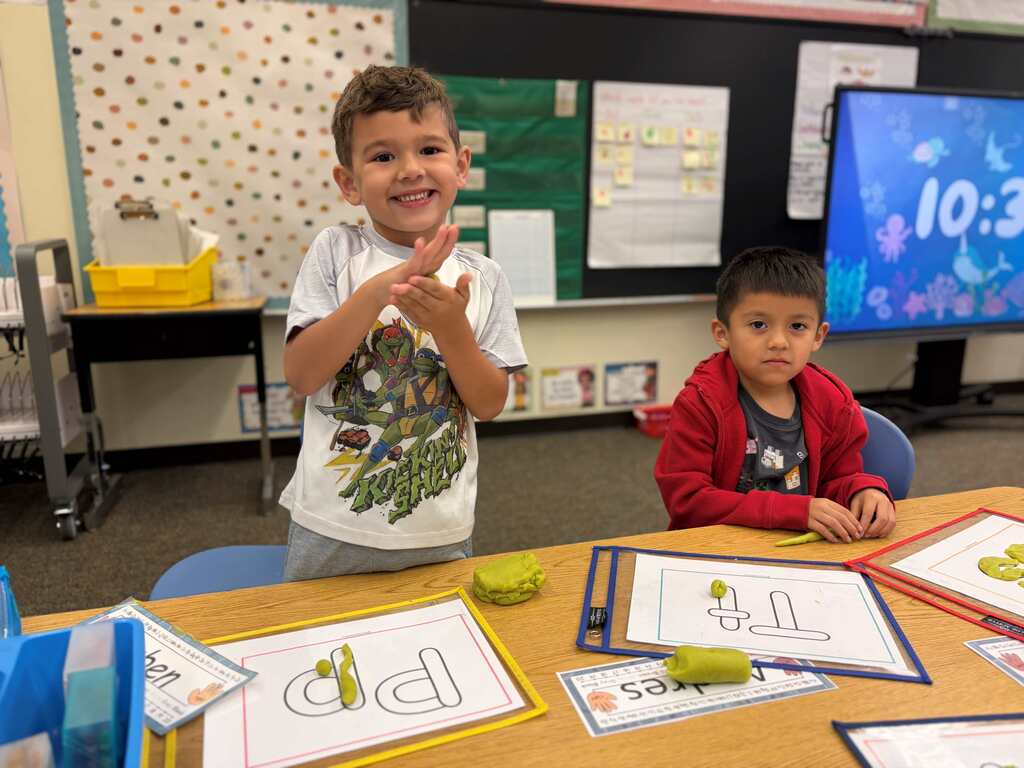 two students working on the letters T and P