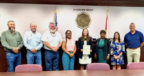 group of men and women smiling for a proclamation photo