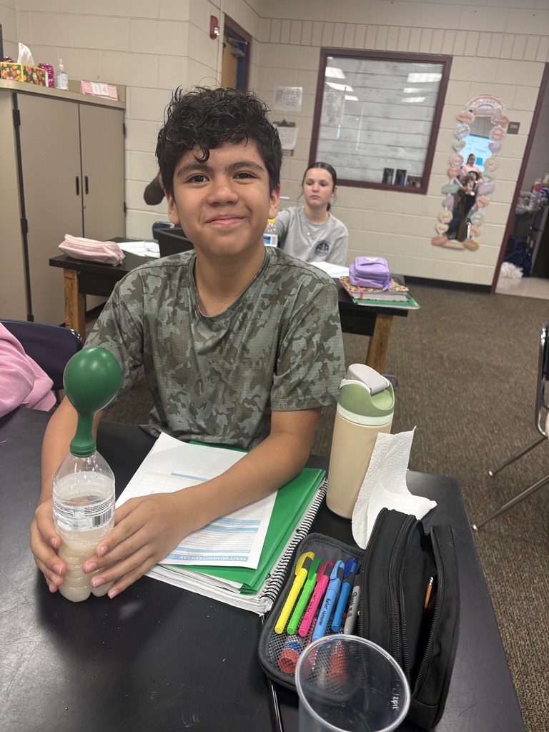male student wearing a camo shirt conducting a science experiment in class