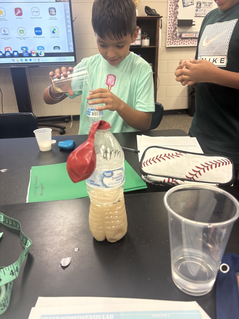 male student wearing a green shirt conducting a science experiment in class