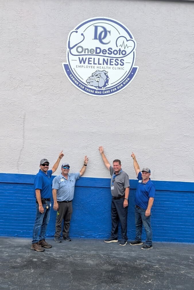 photos of 4 men pointing to a sign on the side of a building