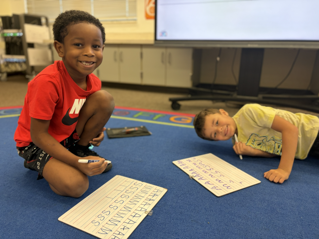two students writing alphabet letters