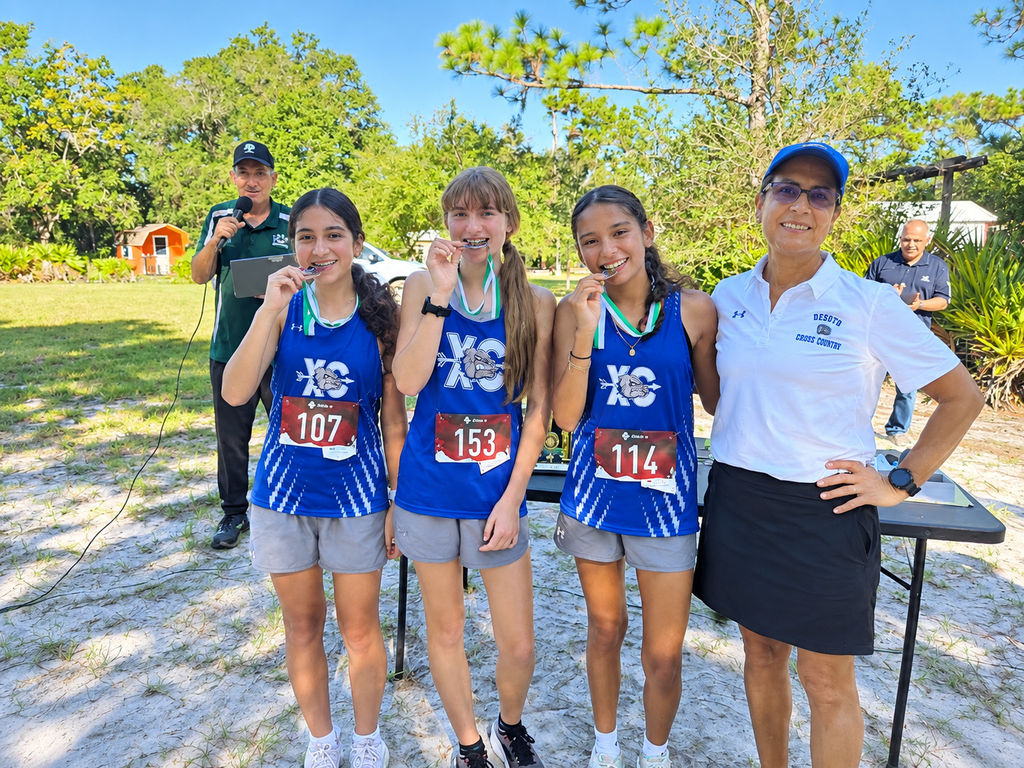 3 XC students posing for a picture with their coach