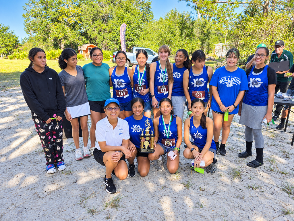 group of DHS XC runners posing for a picture with their coach