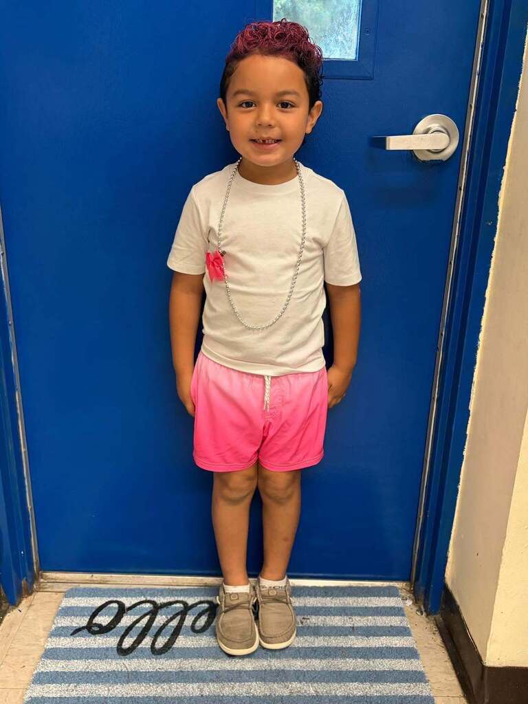 little boy wearing pink and smiling for a picture