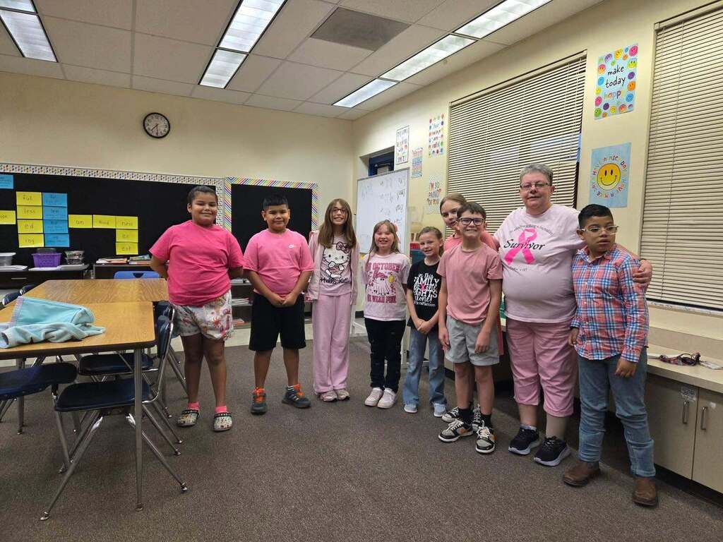 teacher and students wearing pink for breast cancer awareness smiling for a picture