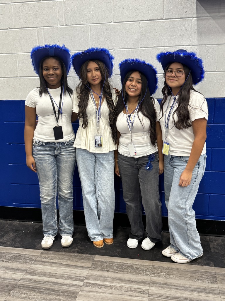4 students wearing blue hats and smiling at pep rally