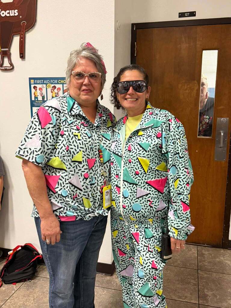 two staff posing in 90s clothes and smiling