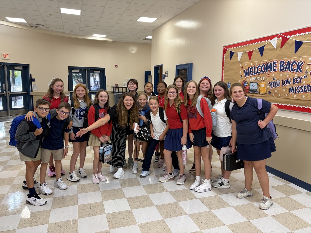 A group of students poses for a photo in a hallway with a "Welcome Back" banner.