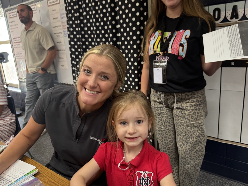 Woman and young girl smiling in classroom. Woman in gray shirt. Child in red shirt. White background.