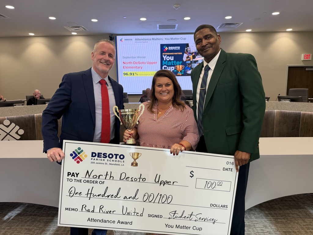 Three adults stand with a large check and a trophy. A woman holds the check, while two men stand on either side of her.