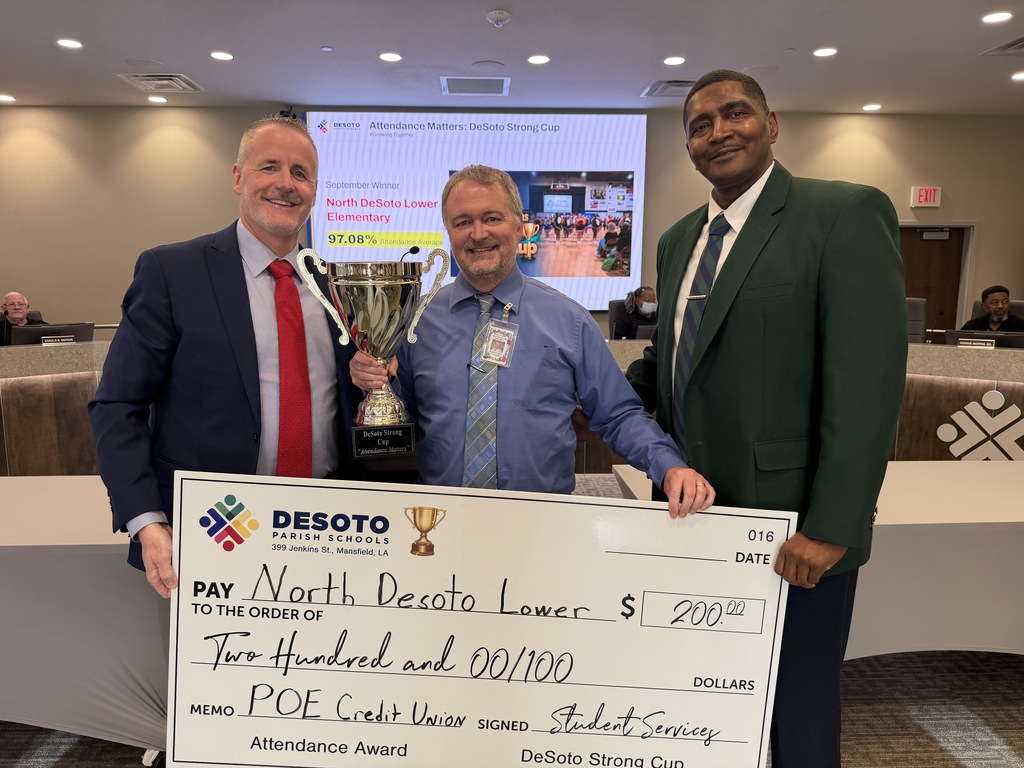 Three men stand in a room with a conference backdrop. One holds a large check, another a trophy.