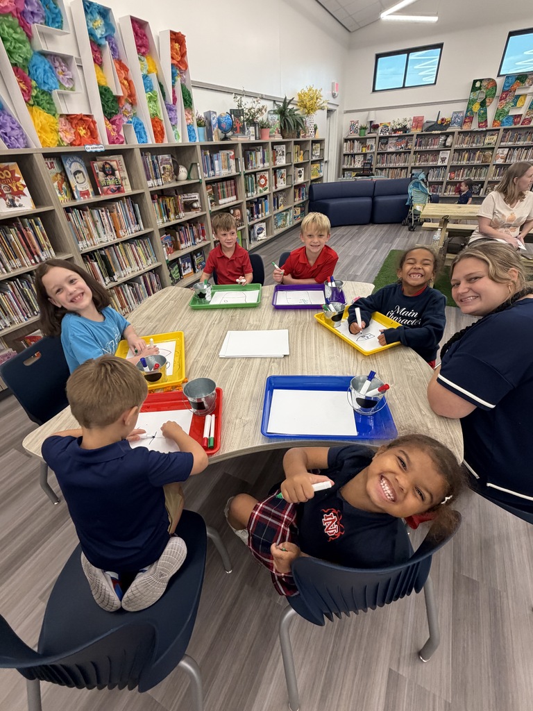 Library setting with children at a table, doing crafts. Trays with markers, paper, and other materials.