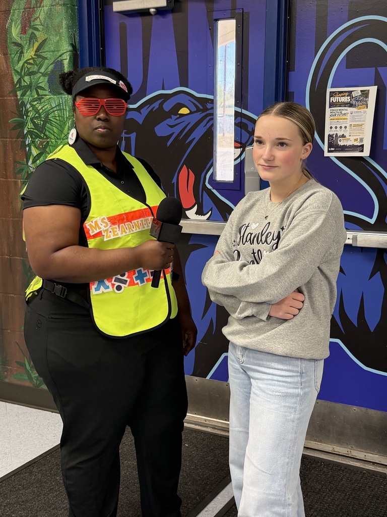 Two people standing in front of a wall with a mural of a black panther.