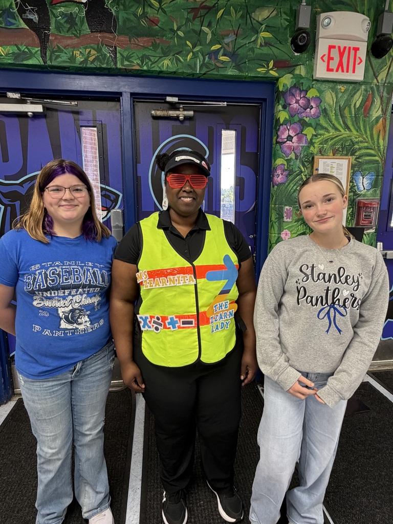 Three individuals, including one in a reflective safety vest, stand before a door with painted artwork.