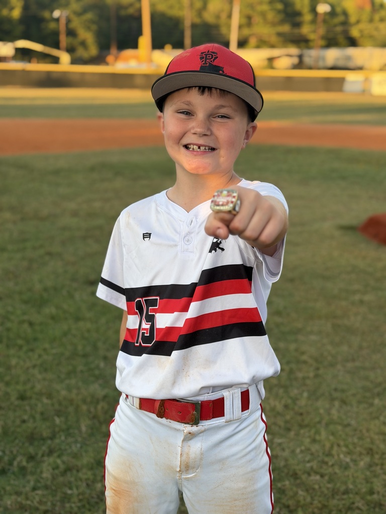 A smiling boy in a baseball uniform shows a baseball glove he holds in his left hand.