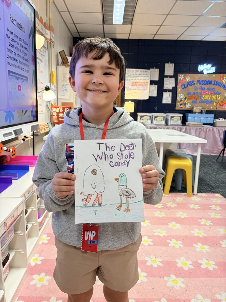 A smiling boy in a gray hoodie holds a poster with a drawing of a bird.