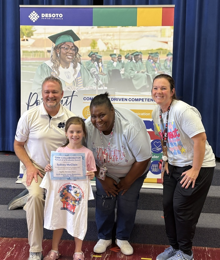 Four adults and a young girl stand for a photo. The girl holds a certificate. Two women wear white shirts, one has a lanyard. Two men wear light-colored shirts.