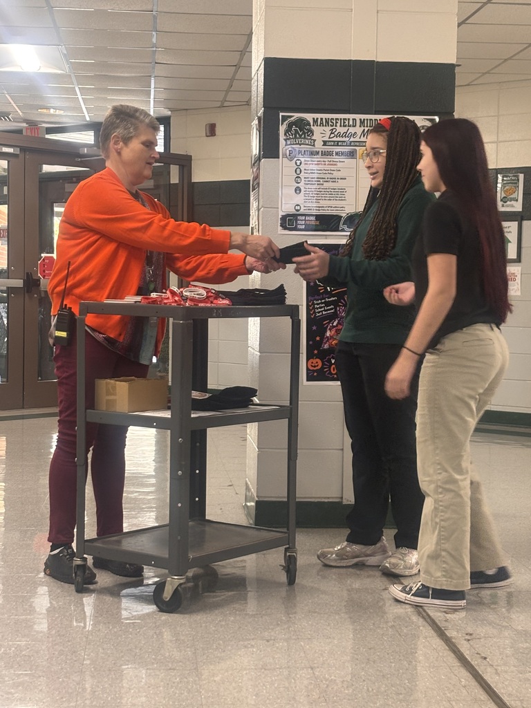 Two women standing next to a man holding hands. The man is wearing a bright orange shirt.