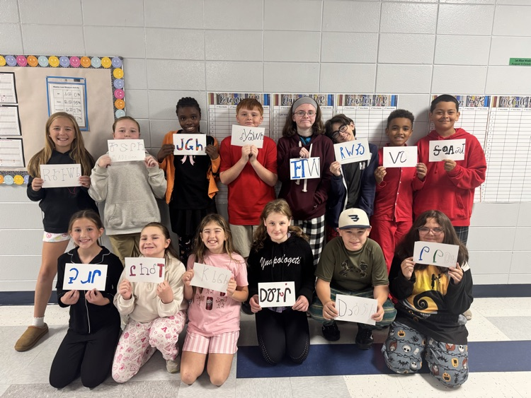 Kids in a classroom hold signs with words like "PUR", "CLOT", "DOTH", "UG", and "TUB" in front of them.