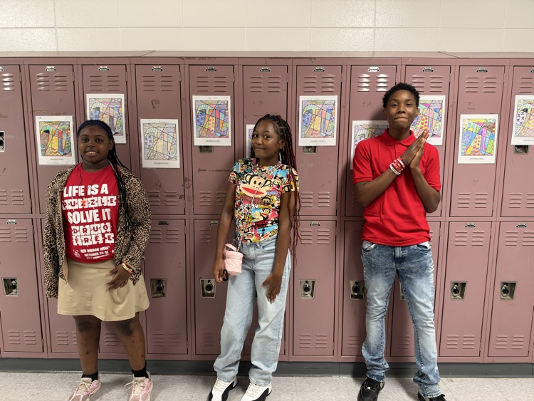 Three students stand before lockers with colorful artwork. A girl in a red shirt makes a peace sign.