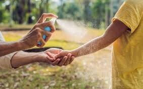Adult spraying child with bug spray.