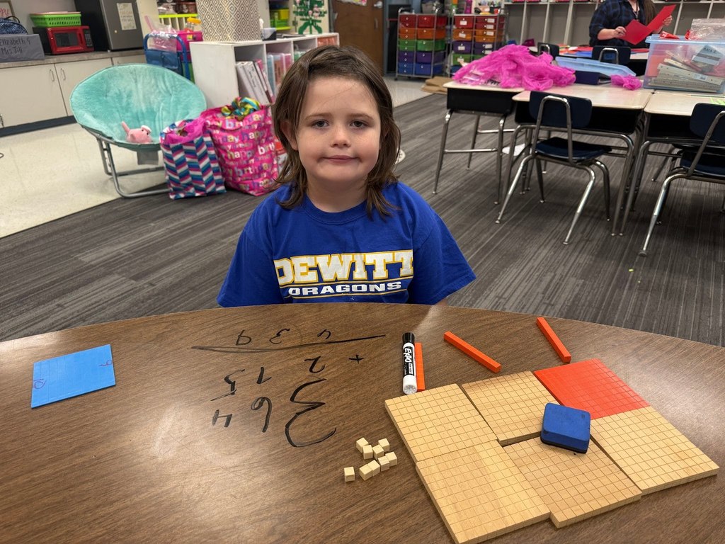 female student using math manipulatives wearing a blue dewitt dragon shirt in a classroom with a christmas tree in the background
