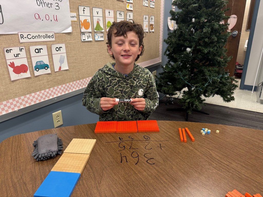 male student using math manipulatives wearing a camo shirt in a classroom with a christmas tree in the background