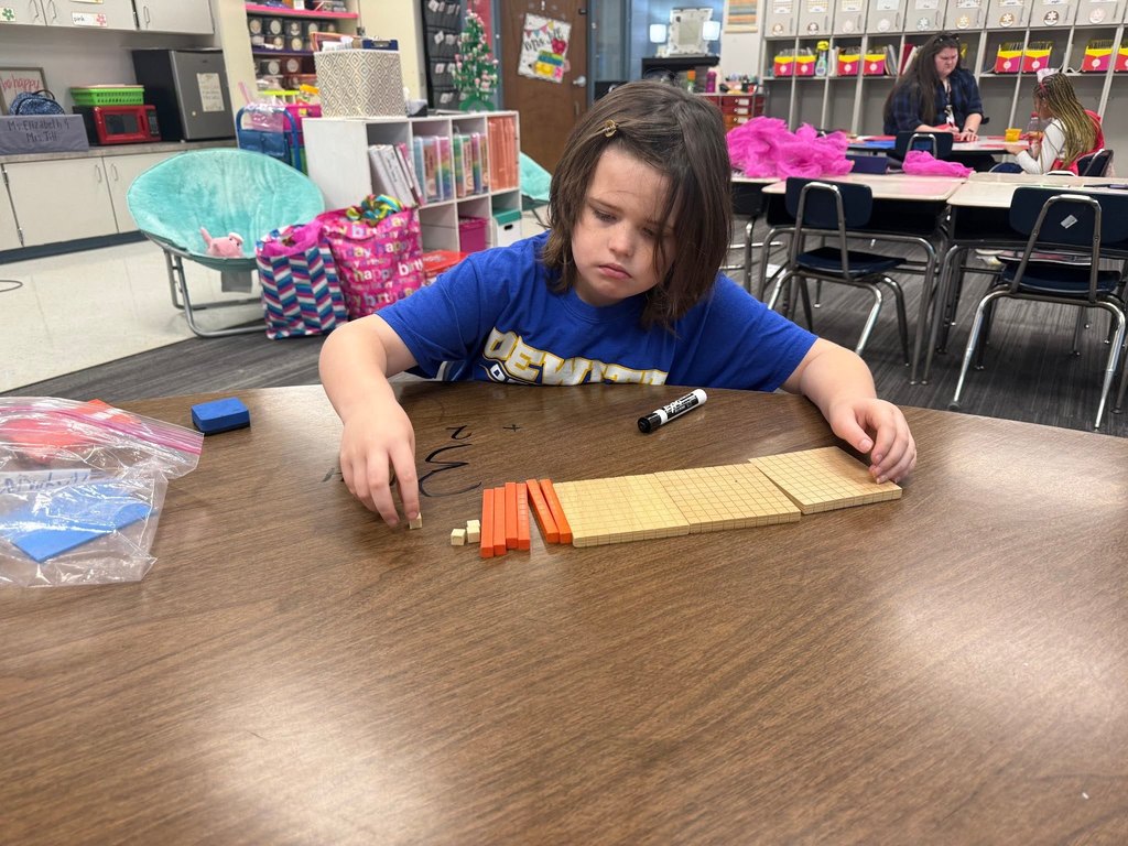 female student using math manipulatives wearing a blue shirt in a classroom at a table